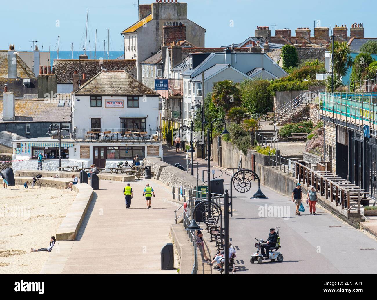 Lyme Regis, Dorset, Regno Unito. 16 maggio 2020. Regno Unito Meteo: La gente comincia a tornare alla spiaggia di Lyme Regis il primo Sabato soleggiato da quando le restrizioni del governo coronavirus sono stati attenuati. Oggi c'erano più persone sul lungomare. Credit: Celia McMahon/Alamy Live News Foto Stock