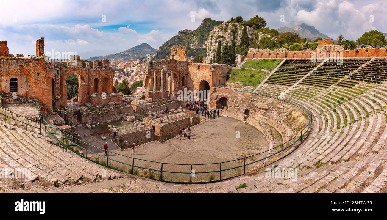 Vista panoramica delle rovine del teatro greco antico, della città vecchia di Taormina e del villaggio di montagna Castelmola in giornata di sole, Sicilia, Italia Foto Stock