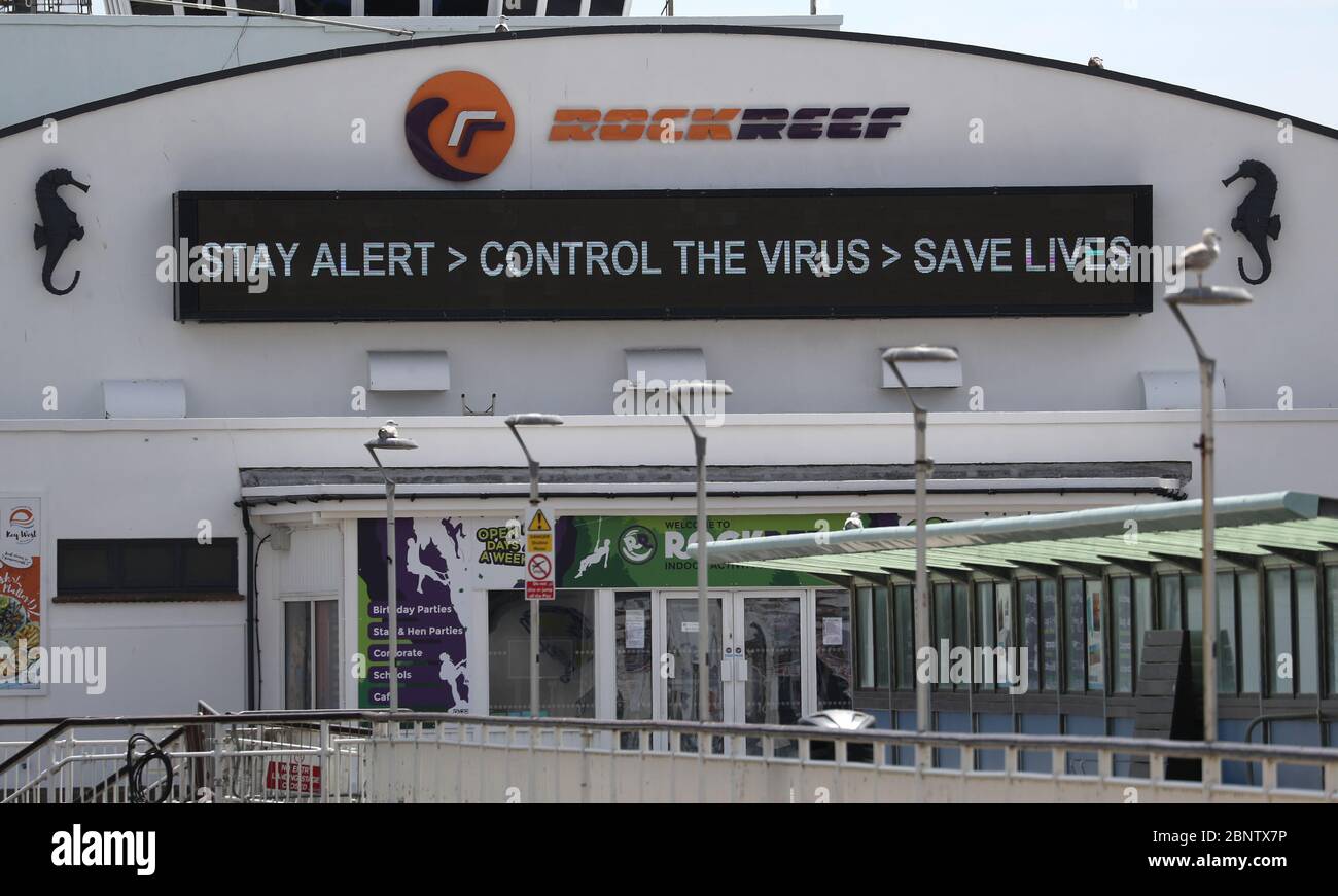 Un segno che dice 'allarme di giorno, controllo del virus, salvare vite' è visto sul molo di Bournemouth, dopo l'introduzione di misure per portare il paese fuori di blocco. Foto Stock