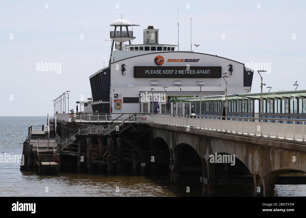 Un cartello che dice 'tenere 2 metri di distanza' è visto sul molo di Bournemouth, dopo l'introduzione di misure per portare il paese fuori dalla serratura. Foto Stock