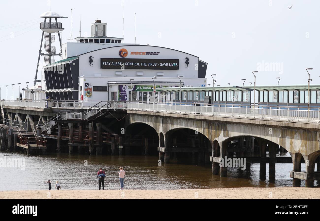 Un segno che dice 'allarme di giorno, controllo del virus, salvare vite' è visto sul molo di Bournemouth, dopo l'introduzione di misure per portare il paese fuori di blocco. Foto Stock