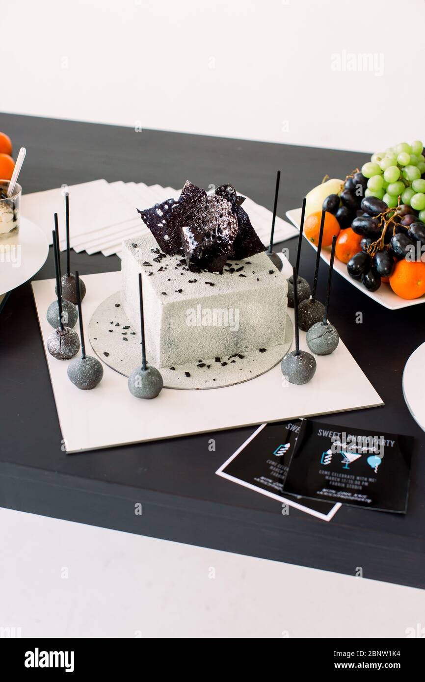 Decorazioni per feste di compleanno. Torta di compleanno decorata in bianco  e nero e frutta fresca sul tavolo nero. Concetto di festa di compleanno  Foto stock - Alamy
