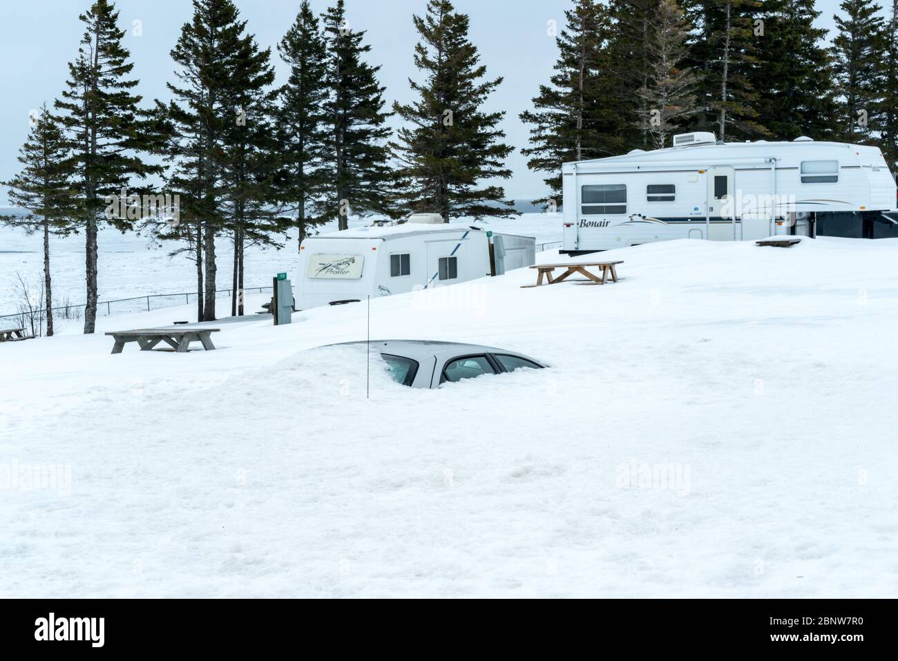 Un'auto si trova completamente sommersa da una riva della neve in un campeggio nel Québec orientale in inverno. Foto Stock