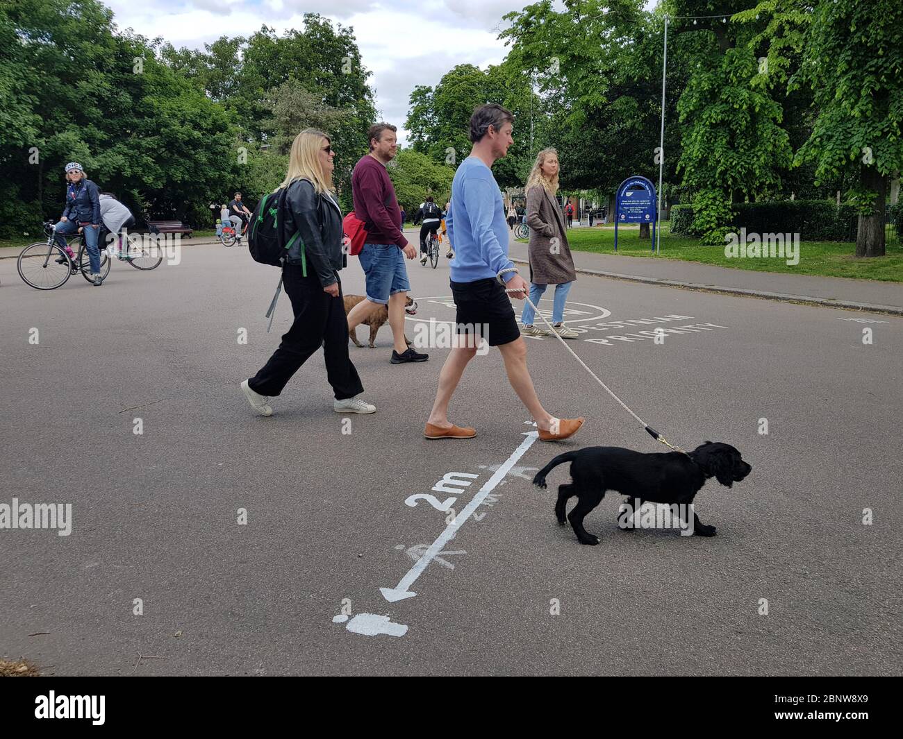 persone che camminano su un cartello di promemoria di allontanamento sociale sulla superficie del victoria park Foto Stock