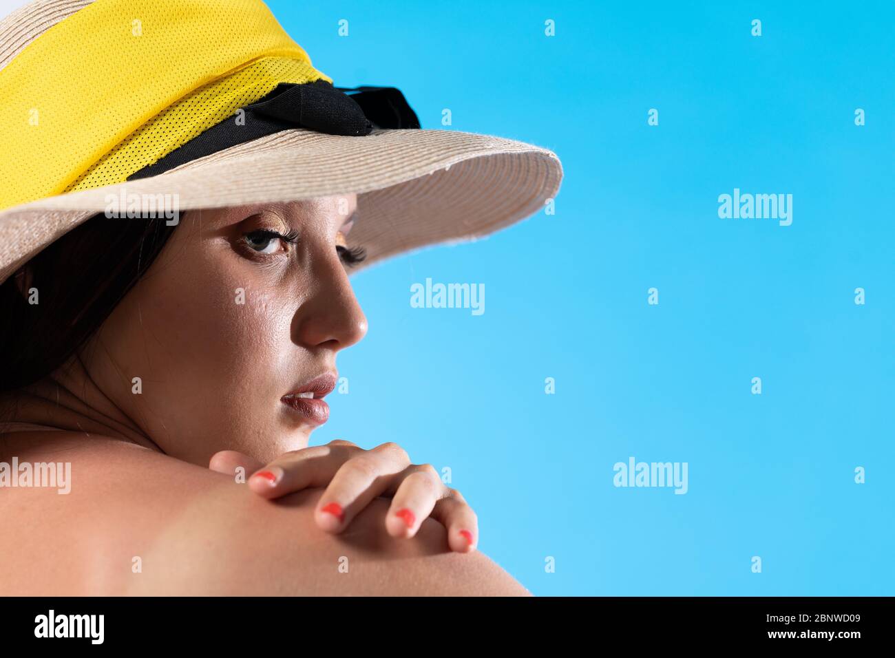 Una giovane ragazza in un cappello su uno sfondo del cielo blu con la mano che tiene il braccio. Foto Stock