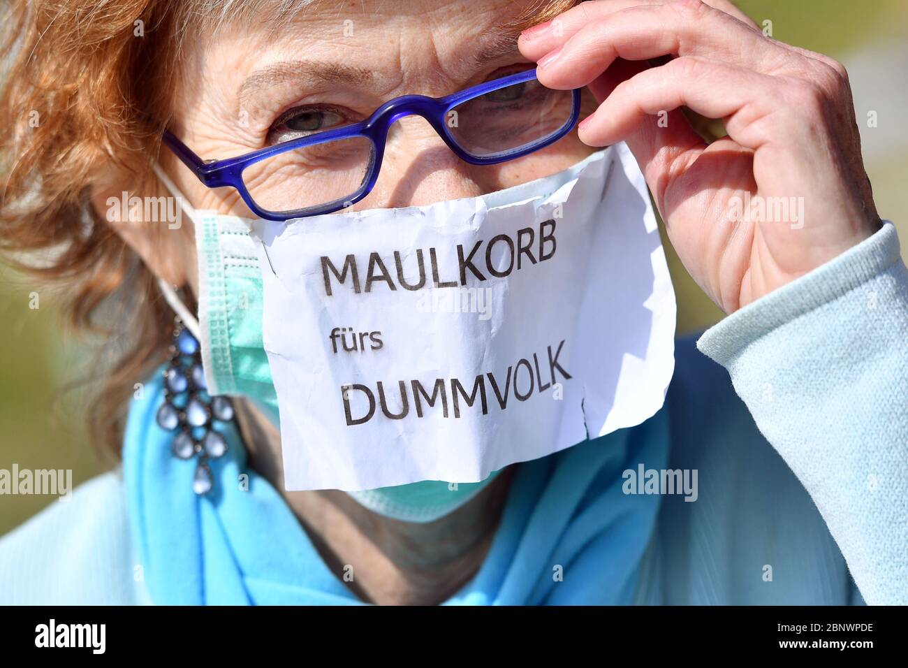Dimostrazione contro corona restrizioni su Theresienwiese a Monaco il 16 maggio 2020. Dimostranti, demo sulla donna con una maschera facciale, maschera su cui è allegata una nota: MAULKORB FUERS DUMMVOLK. | utilizzo in tutto il mondo Foto Stock