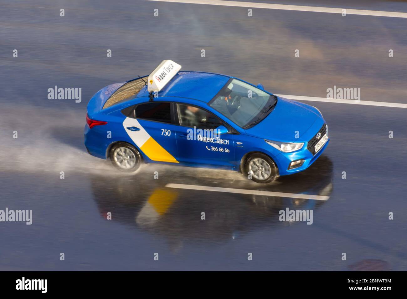 Auto blu passeggeri Yandex Taxi ride sulla pioggia bagnata spray autostrada vista aerea. Russia, San Pietroburgo. 15 maggio 2020 Foto Stock