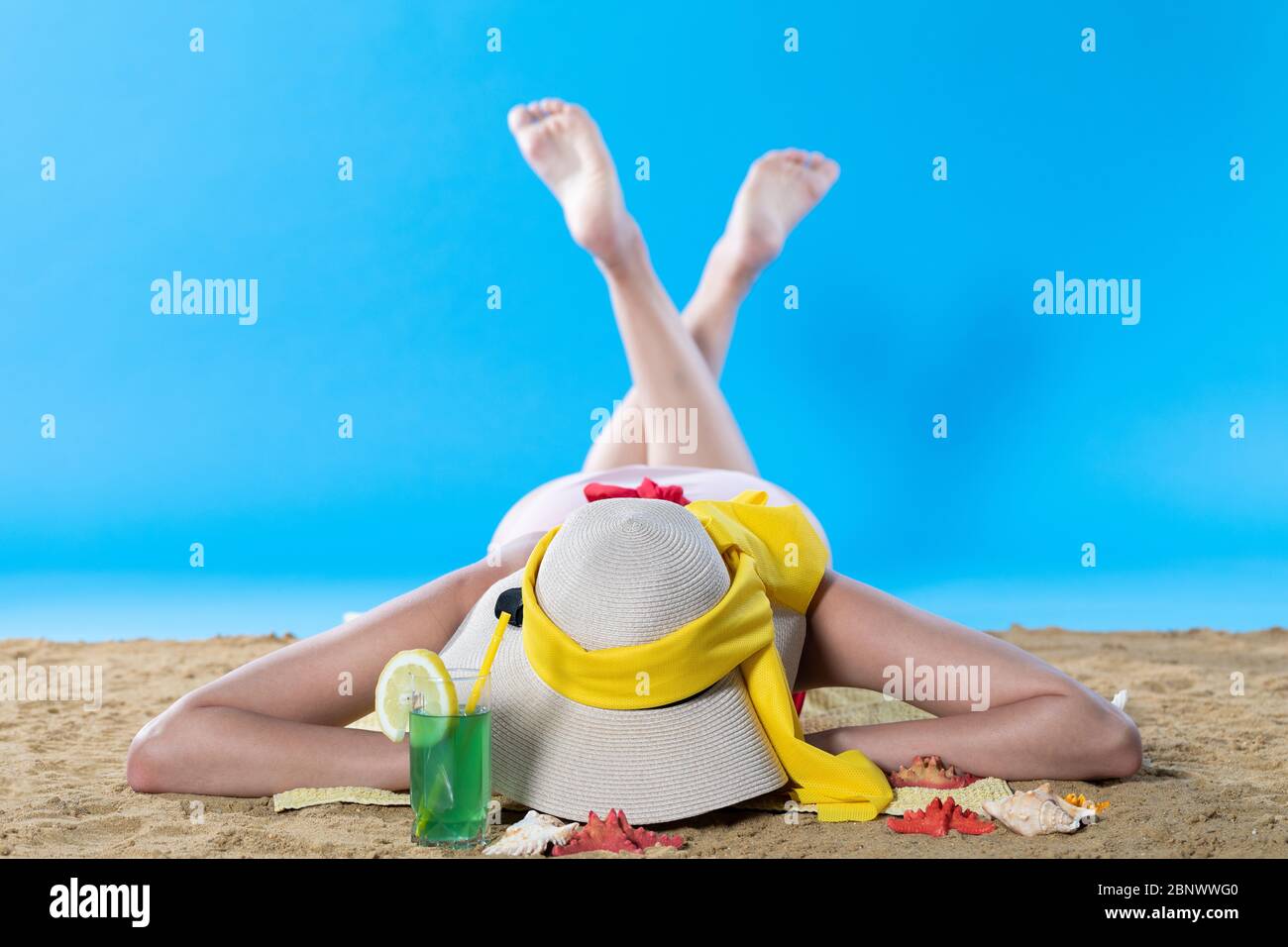 Mentre si prende il sole sulla spiaggia, un adolescente beve una bevanda alcolica fredda. Foto Stock