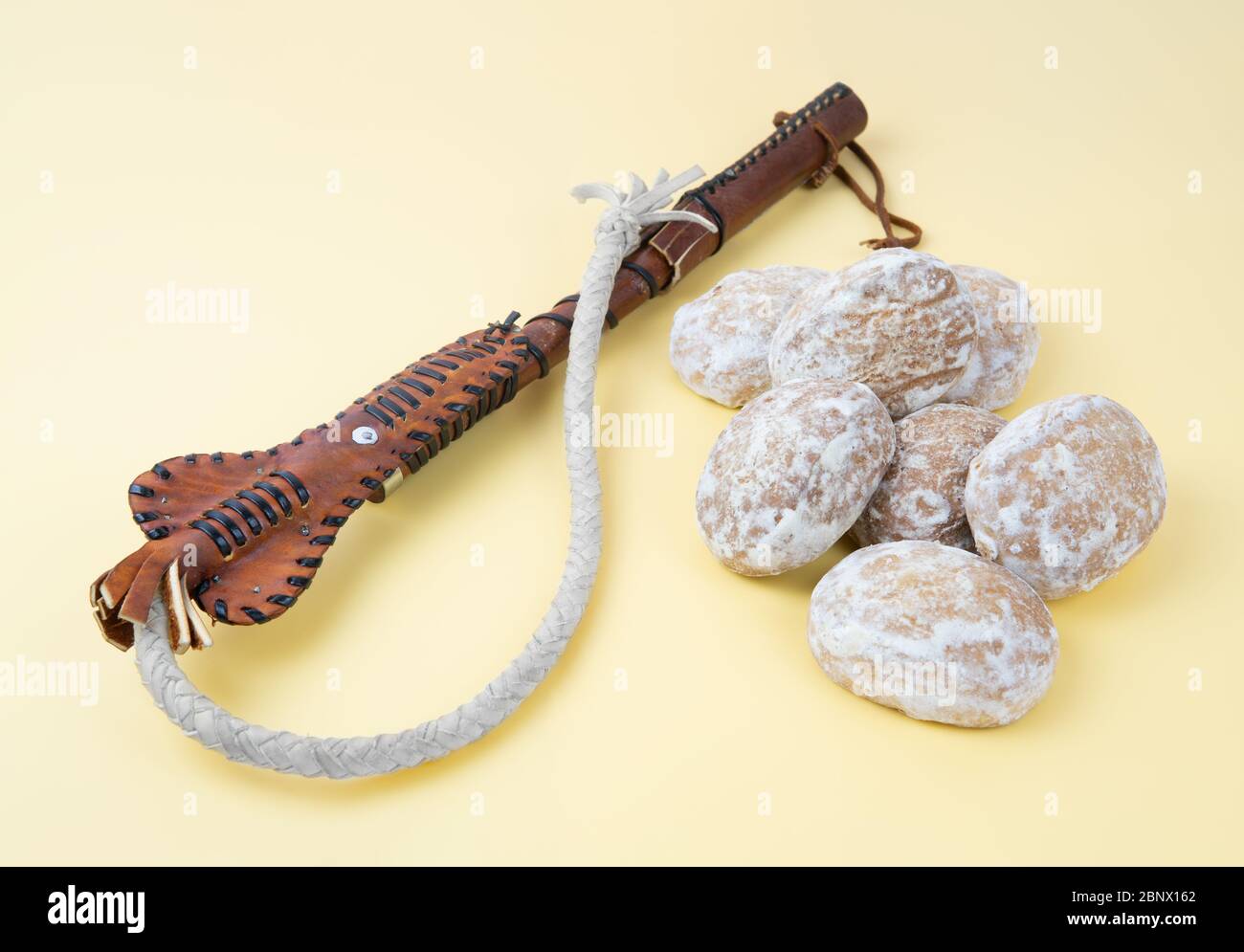 Frusta e pan di zenzero su uno sfondo neutro. Concetto di minacce e promesse. Il metodo di incoraggiamento e di punizione è conosciuto come carota e bastone. Foto Stock