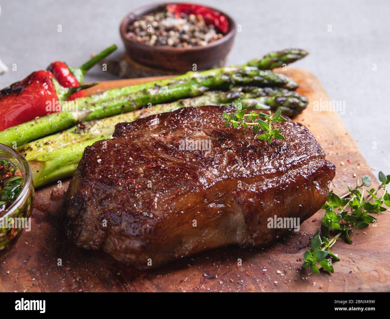 bistecca di manzo arrosto, montone con pepe di asparagi su un tagliere, spezie, grigliate Foto Stock