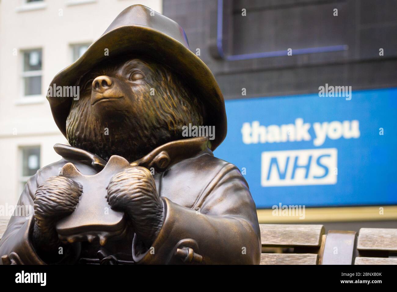 Londra, Regno Unito - 15 maggio 2020: Una statua di Paddington Bear mangiare un panino a Leicester Square, di fronte a un cartello Thank You NHS Foto Stock