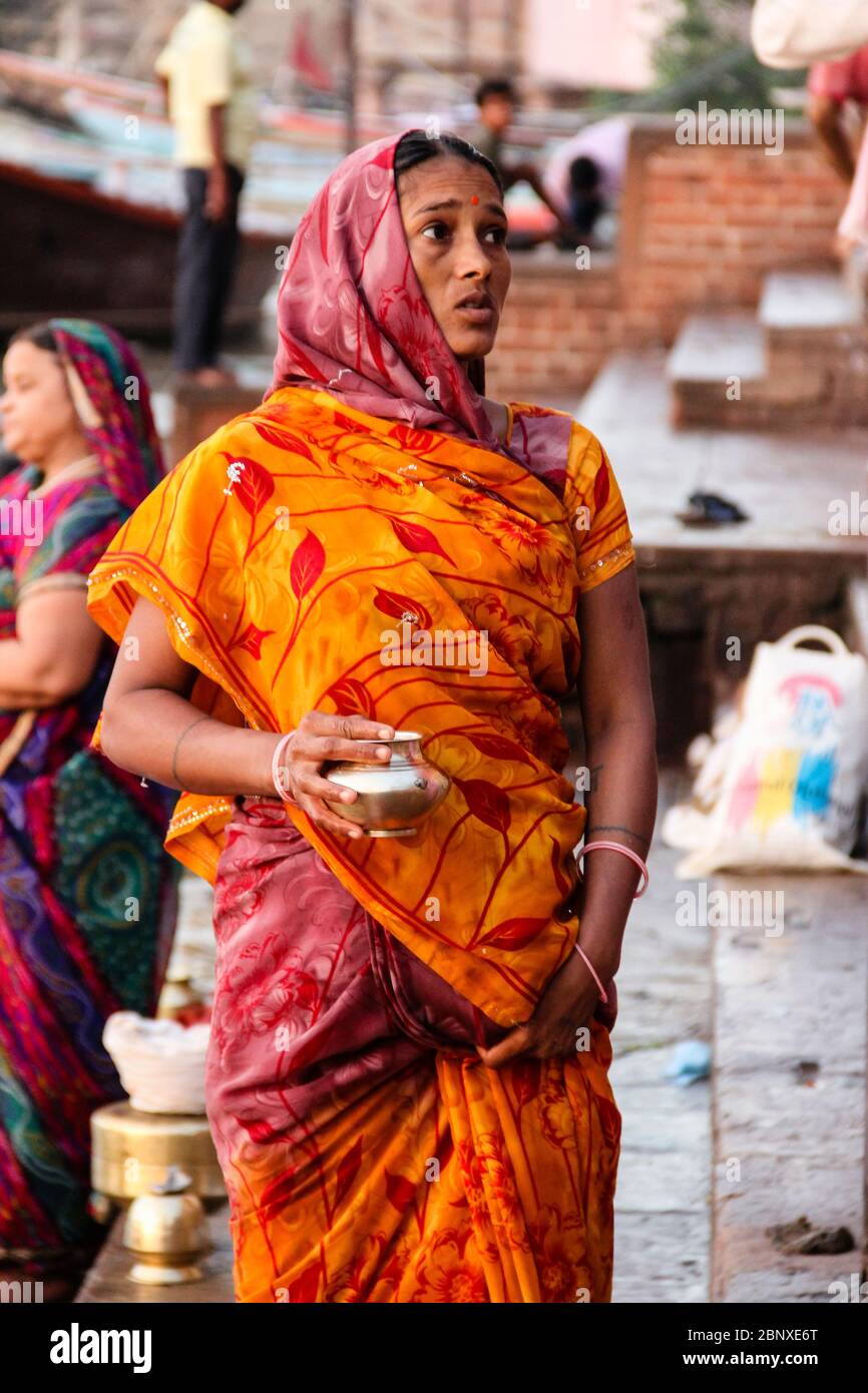 India, Varanasi - Stato di Uttar Pradesh, 31 luglio 2013. Una giovane donna, con abiti colorati, contiene una piccola pentola d'acqua dal Gange - il fiume sacro dell'India. Foto Stock