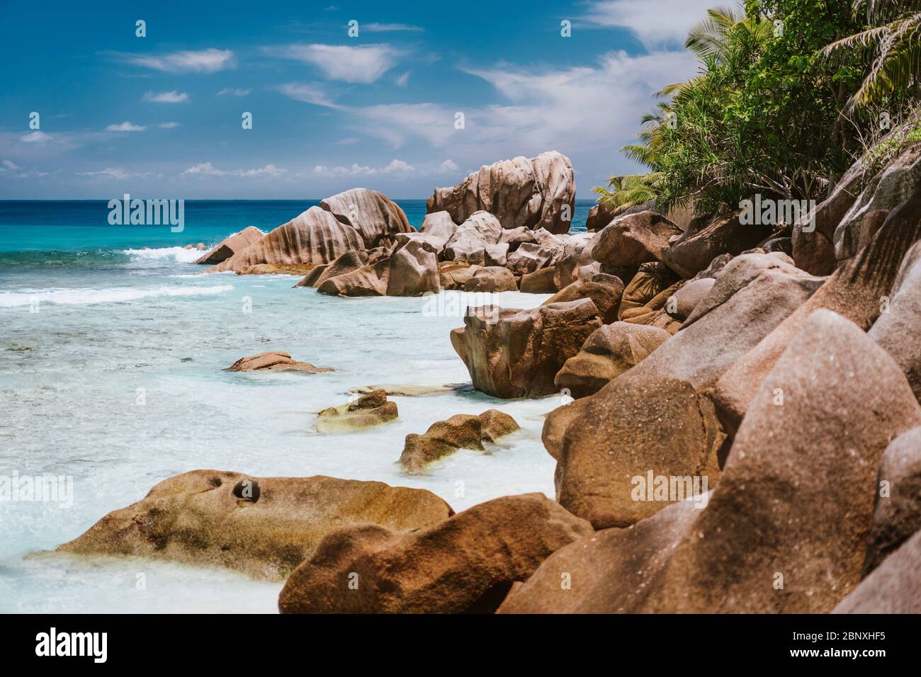 La Digue, Isole Seychelles. Laguna oceanica turchese sulla famosa spiaggia di Anse Cocos con formazioni rocciose di granito Foto Stock