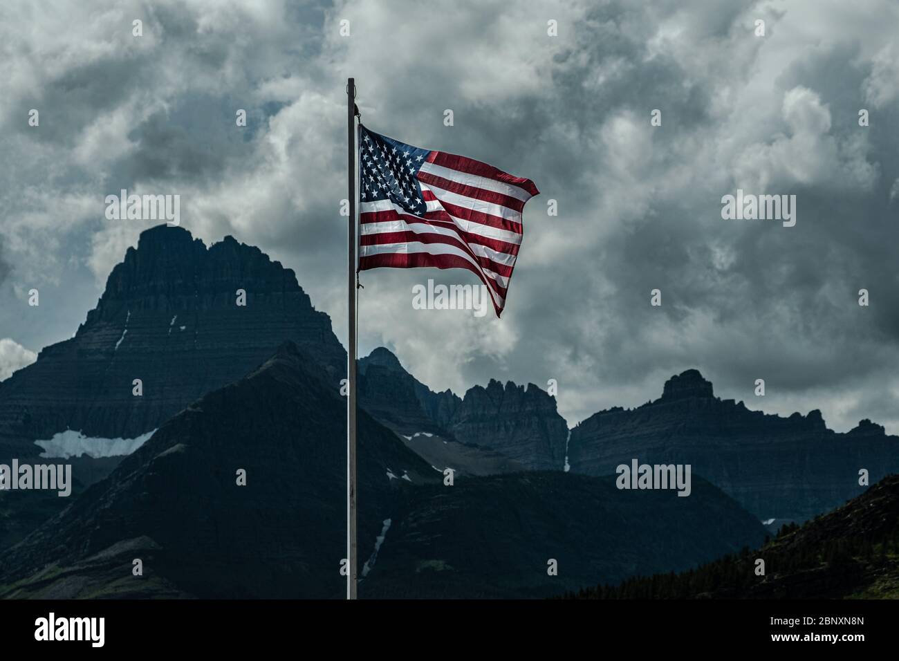 2709 Old Glory, la bandiera americana, si erge contro un cielo tempestoso sul lago Swiftcurrent al Glacier National Park - Montana Foto Stock