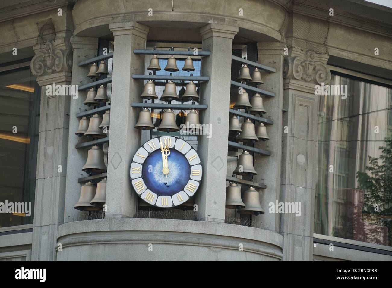 Glockenspiel a Zurigo, campane di varie dimensioni poste intorno ad un orologio all'angolo di un edificio storico da vicino. Le campane suonano una melodia. Foto Stock