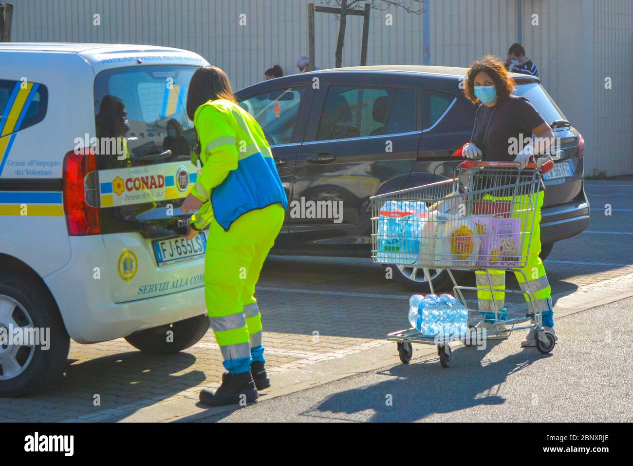 Italia, 04/08/20: Due paramedici volontari italiani in uniforme indossando maschera protettiva del coronavirus fanno generi alimentari per gli anziani e i malati. Pandemia quotidiana Foto Stock