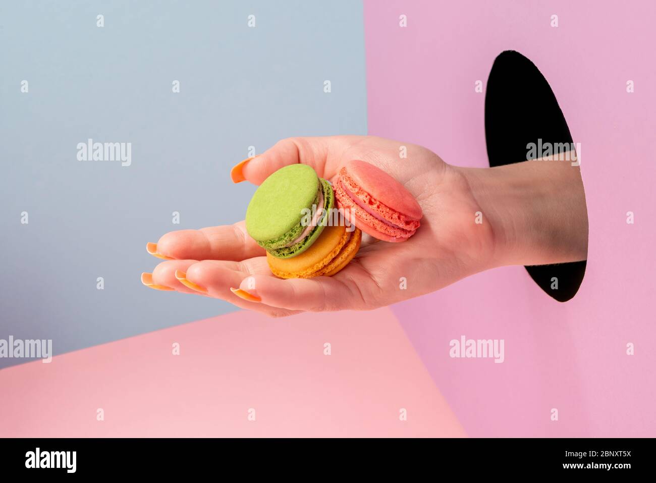Primo piano sulla mano della donna che mostra macaron colorati Foto Stock