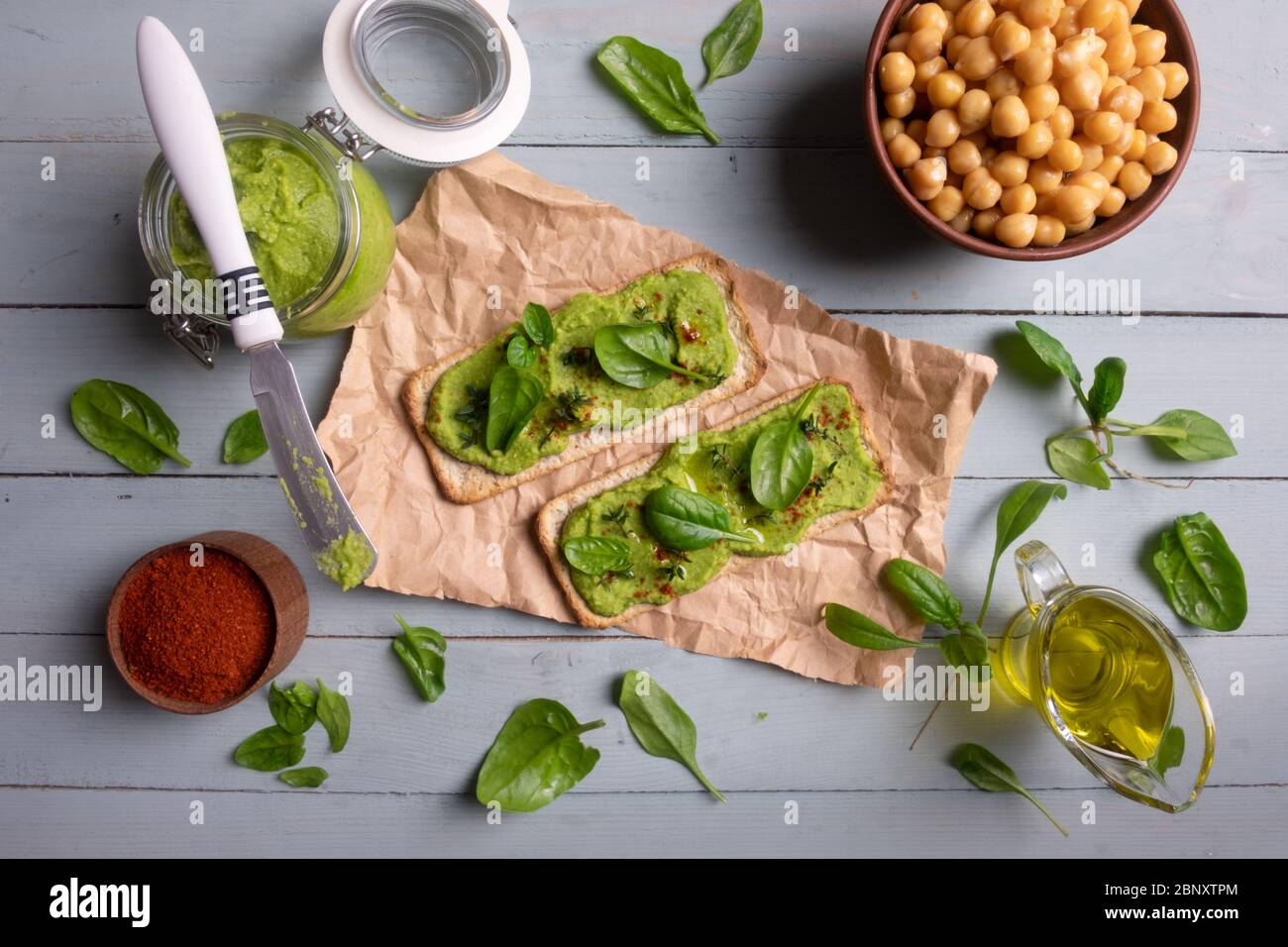 Due cracker con humus di spinaci verdi su tavola di legno. Disposizione piatta. Concetto di hummus. Fotografia di cibo Foto Stock