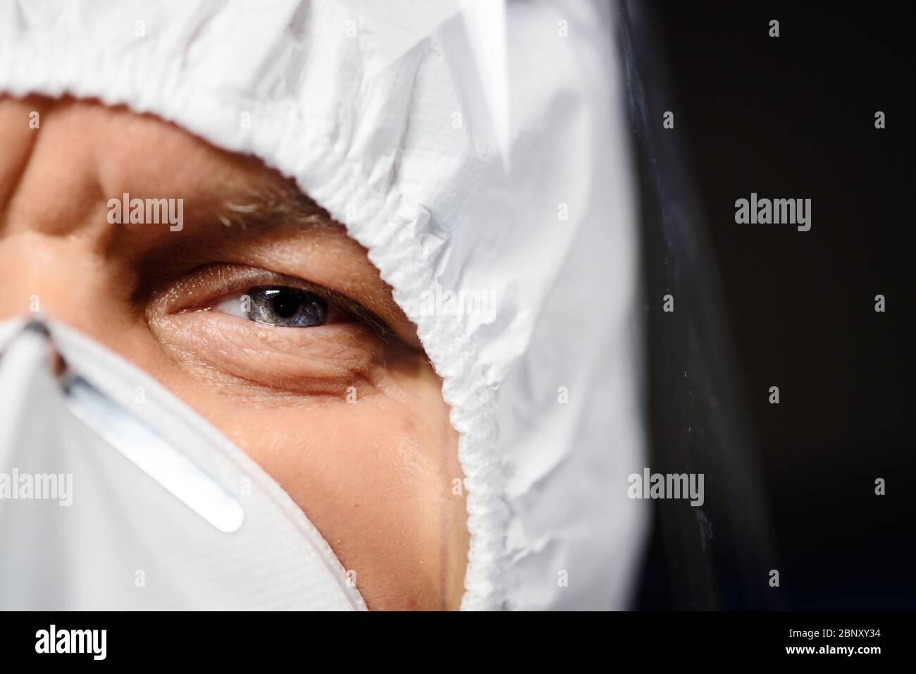 Serio medico in tuta protettiva e maschera ti guarda Foto Stock