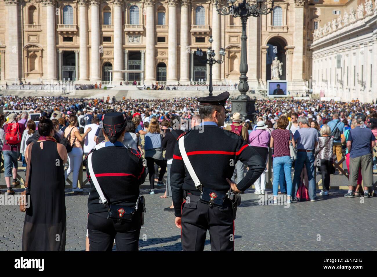 Poliziotto e poliziotto italiani sovrintende alla grande folla di San Pietro Basilica in attesa di ascoltare e vedere il Papa sul Schermo gigante, Roma, Italia Foto Stock