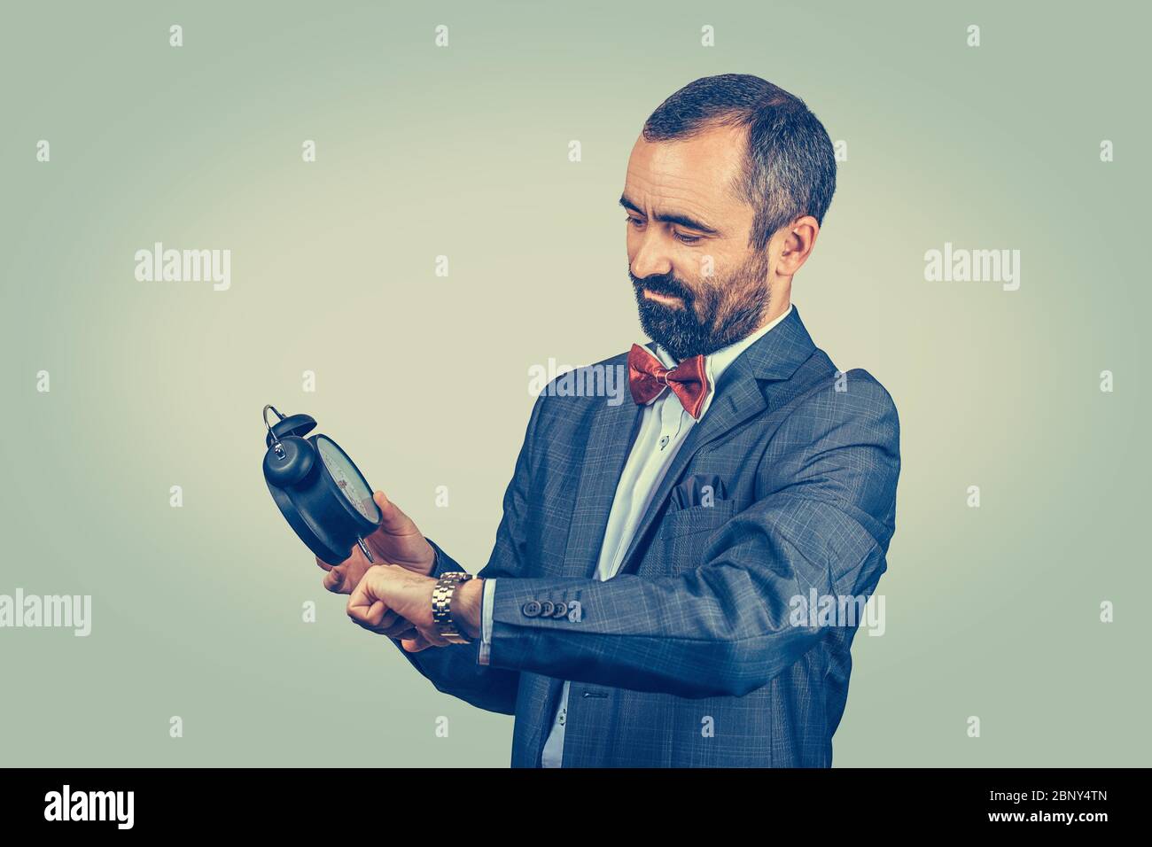 Uomo bearded con sveglia che guarda l'orologio da polso che confronta e  imposta l'ora. Modello con cuscinetti da corsa misti isolato su sfondo  verde giallo Foto stock - Alamy