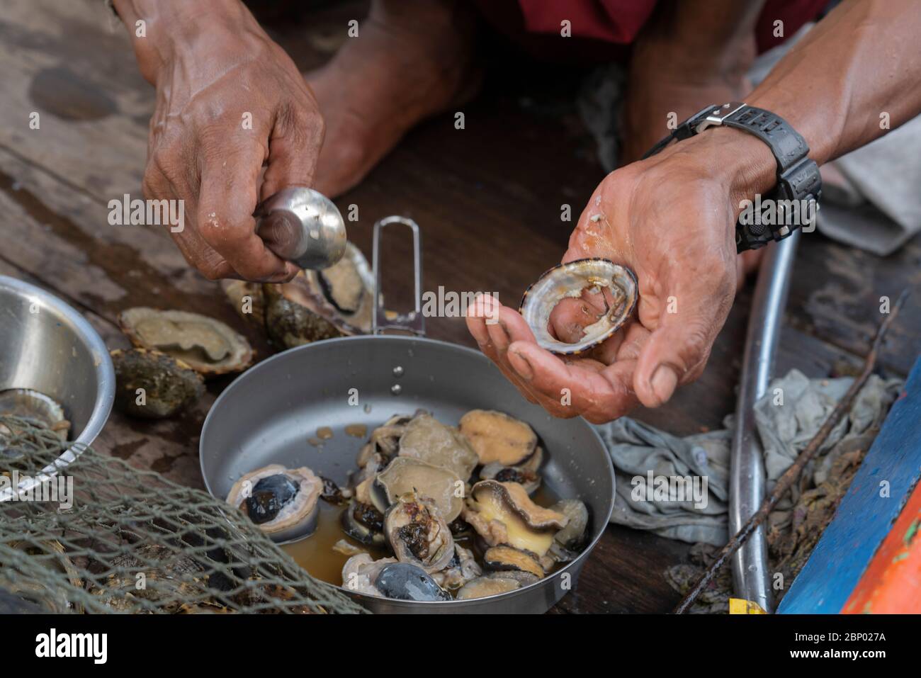 Le popolazioni indigene cucinano conchiglie fresche in barca Foto Stock