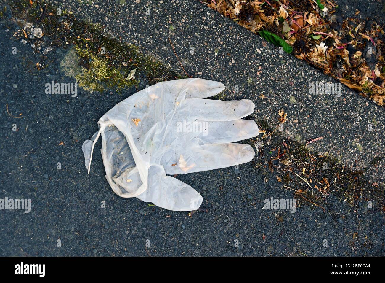Guanti protettivi scartati sulla carreggiata. Foto Stock