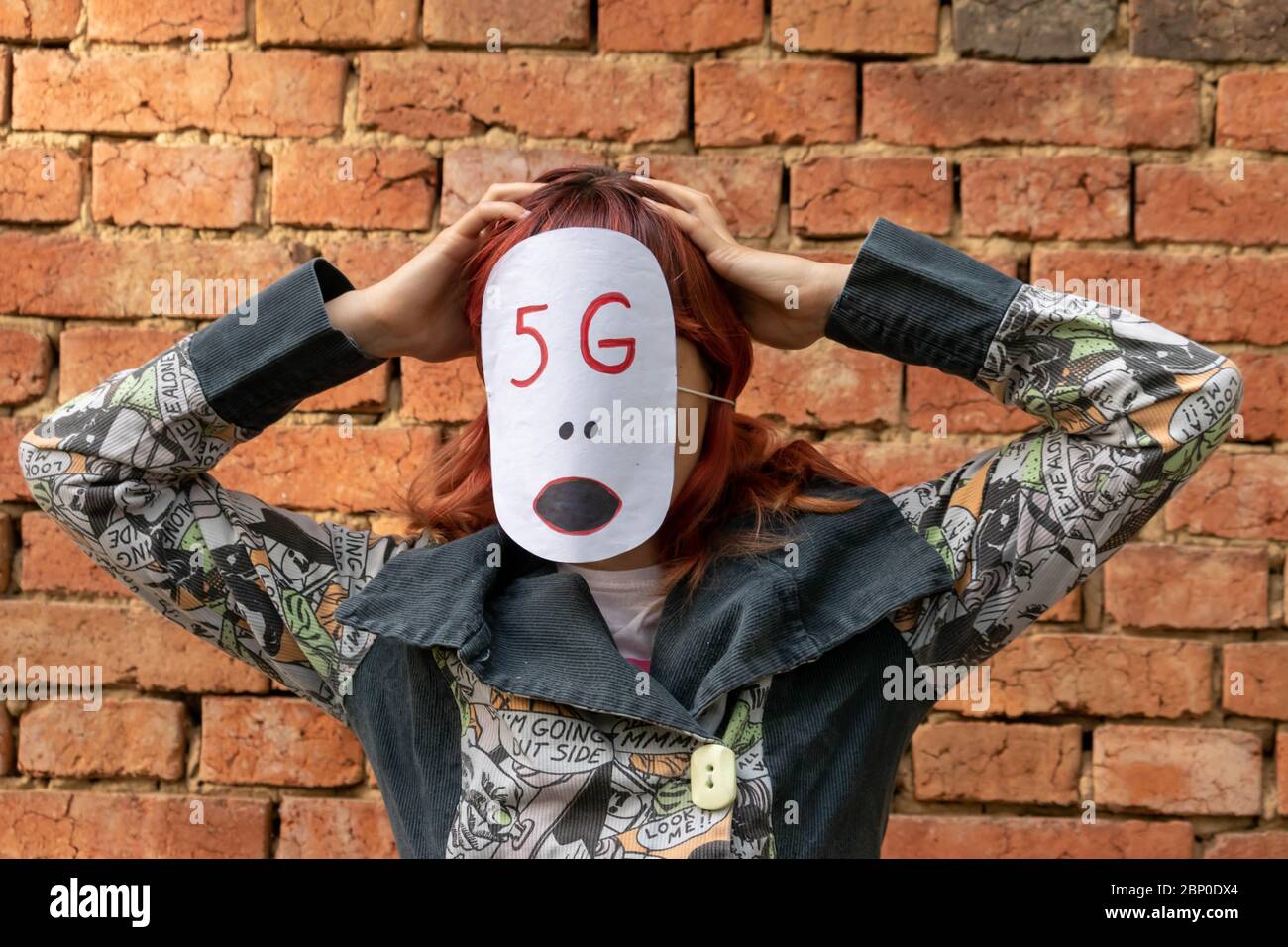Ragazza con 5 g maschera sul viso che mostra i pericoli della tecnologia di rete 5g. Persona che è mente controllata da Internet. Teoria della cospirazione su nuovi tecnici dannosi Foto Stock