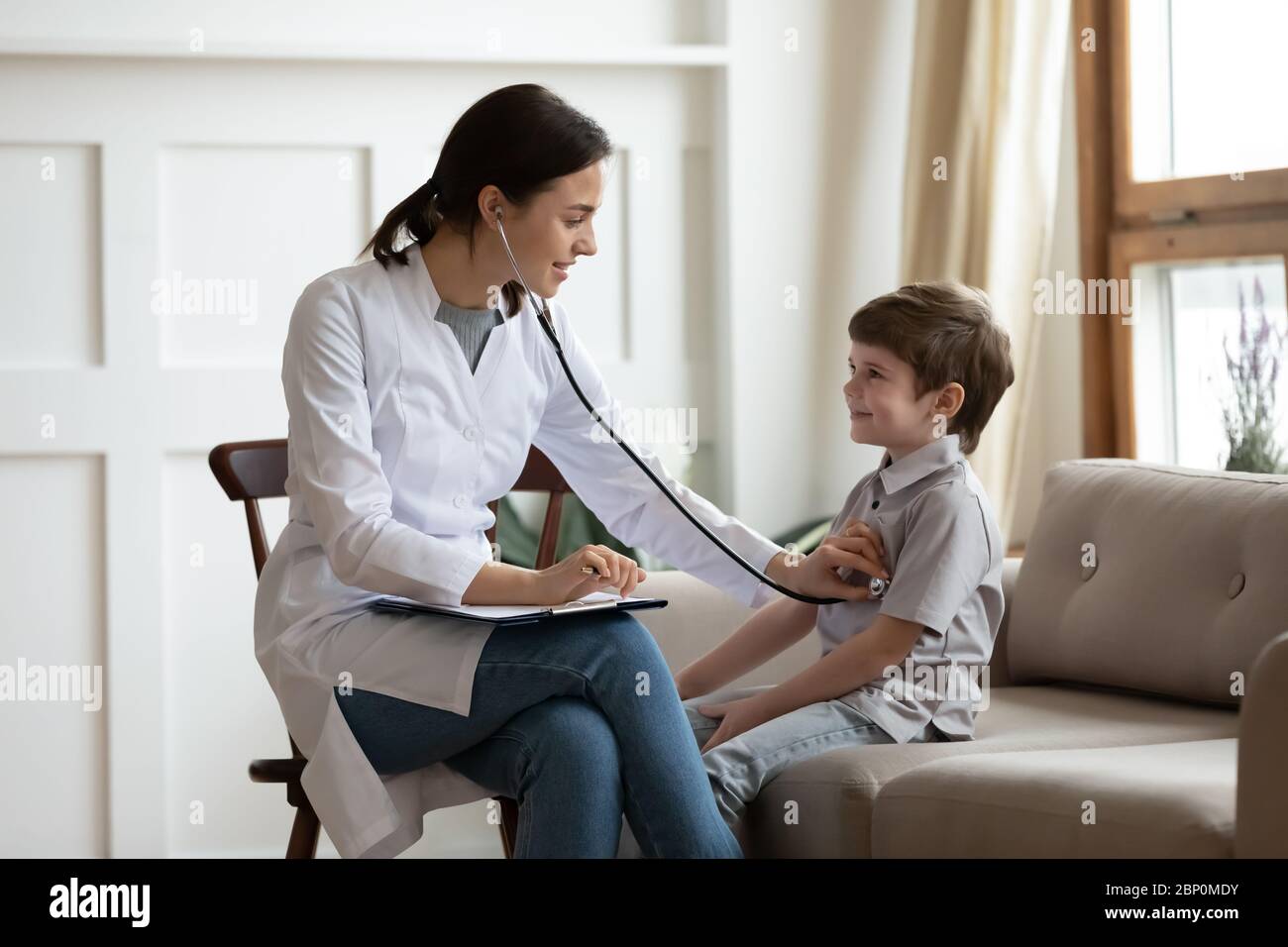 Dottore femminile attento ascoltare il cuore del bambino al check-up Foto Stock