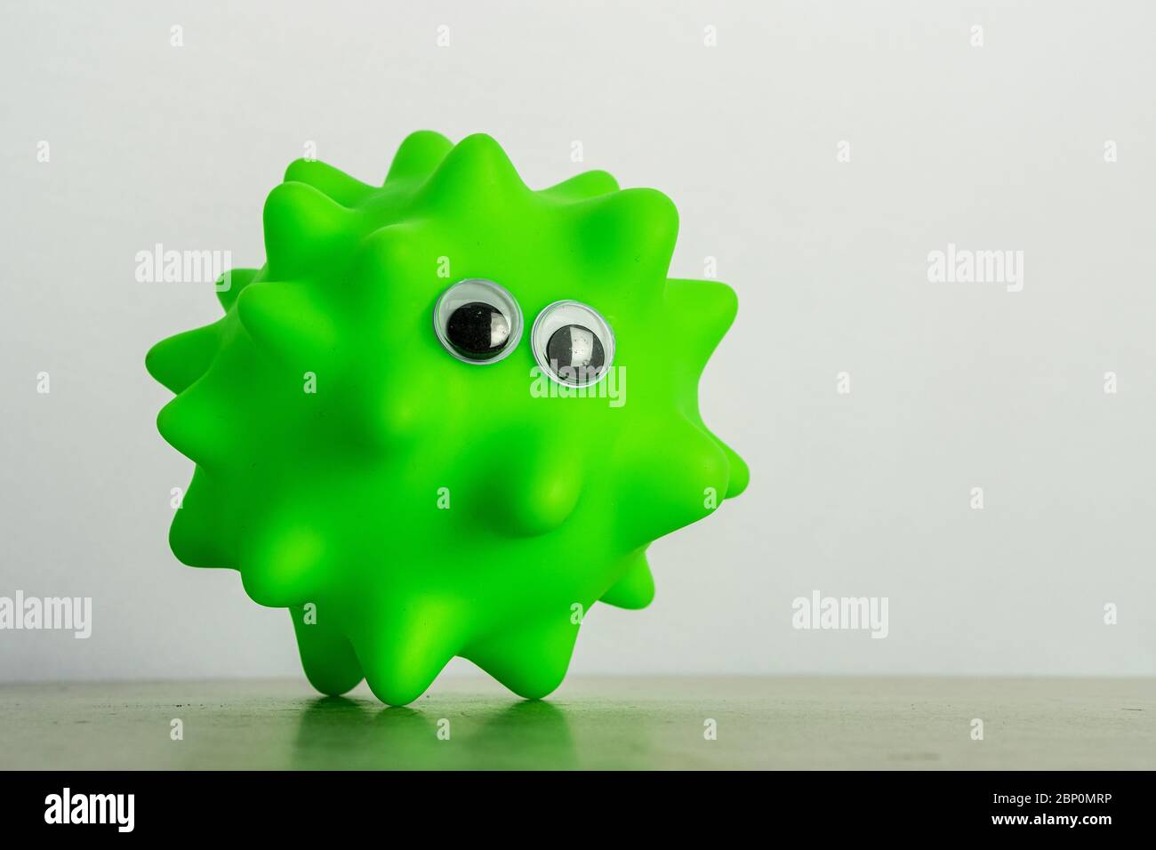 Un giocattolo verde per cani con occhi come simbolo di un virus o batteri Foto Stock