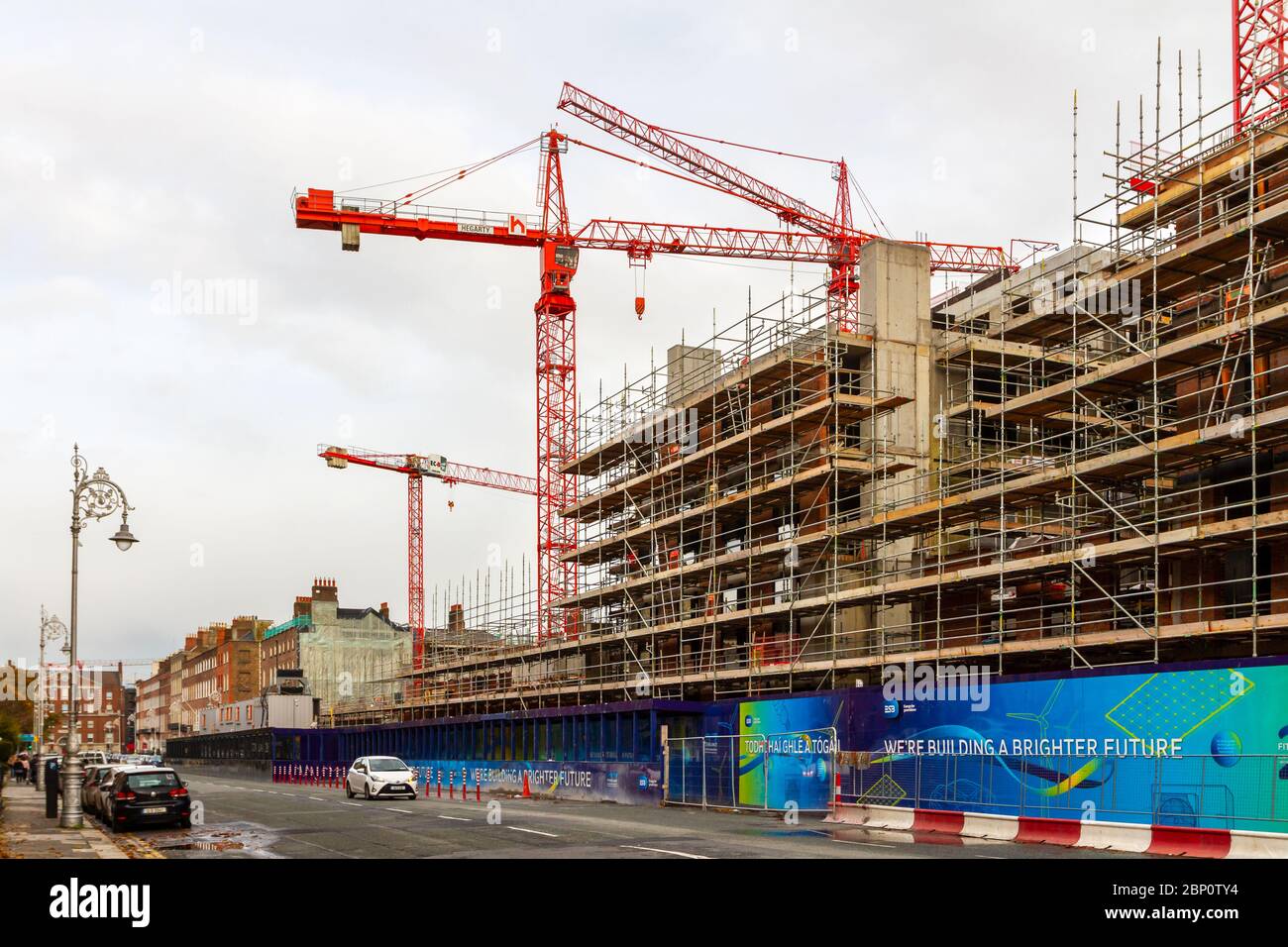 Costruzione gru di costruzione alla riqualificazione di edifici 'ESB' nel centro della città con segnaletica 'costruire un futuro migliore'. Dublino, Irlanda Foto Stock