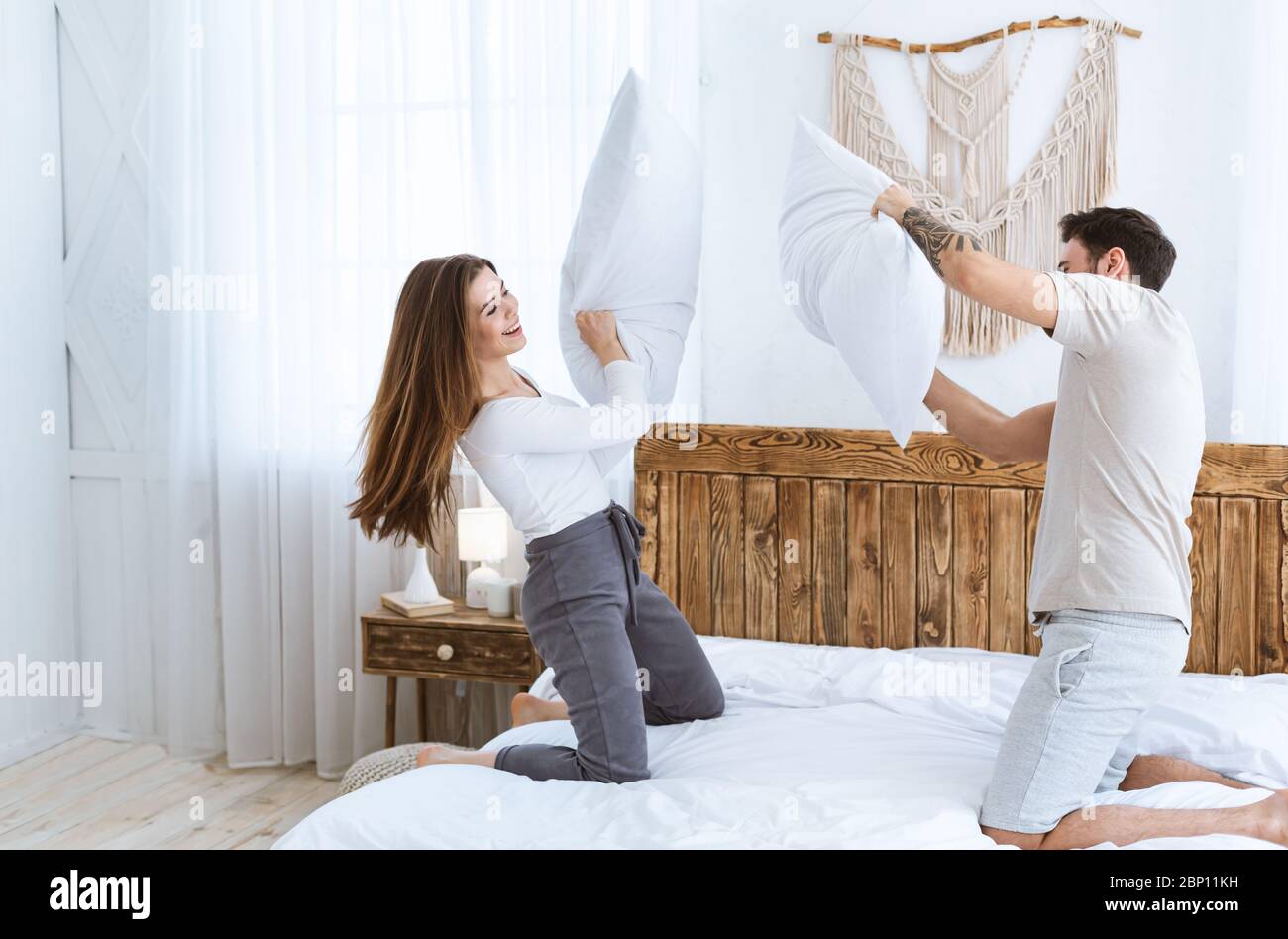 Le coppie giovani si divertono in camera da letto e nei cuscini combatte Foto Stock