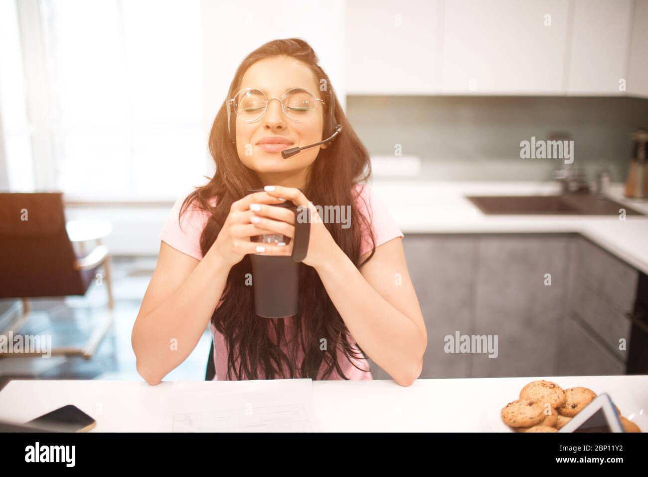 Si sente pieno Zen, pace e tranquillità. Bella donna dai capelli neri lavora da casa. Un dipendente si trova in cucina e ha molto lavoro su un computer portatile Foto Stock