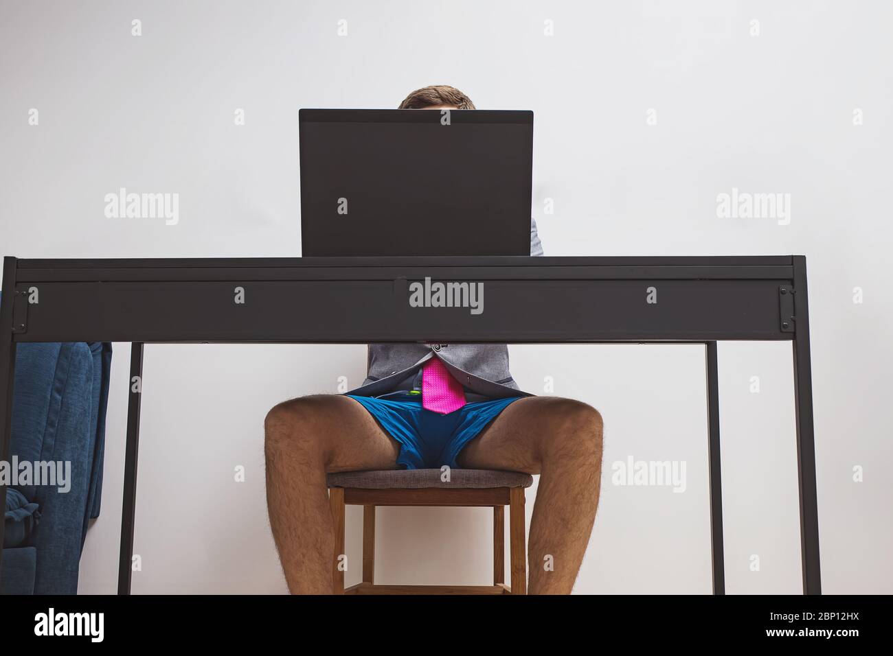 Uomo che indossa una giacca e un paio di shorts blu mentre lavora con il suo laptop. Foto Stock