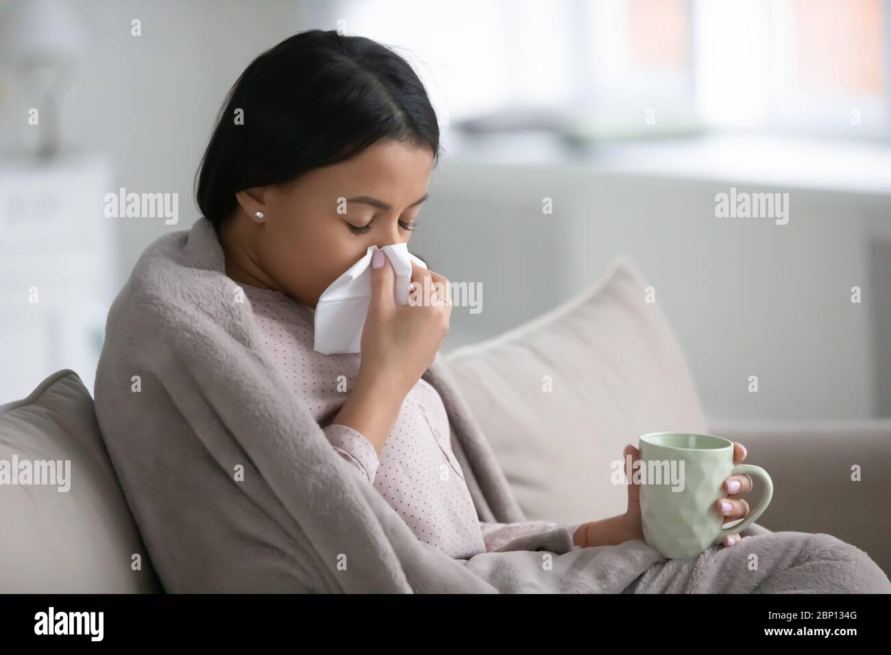 Donna africana avvolta in plaid, botta bevande al naso medicina fredda Foto Stock