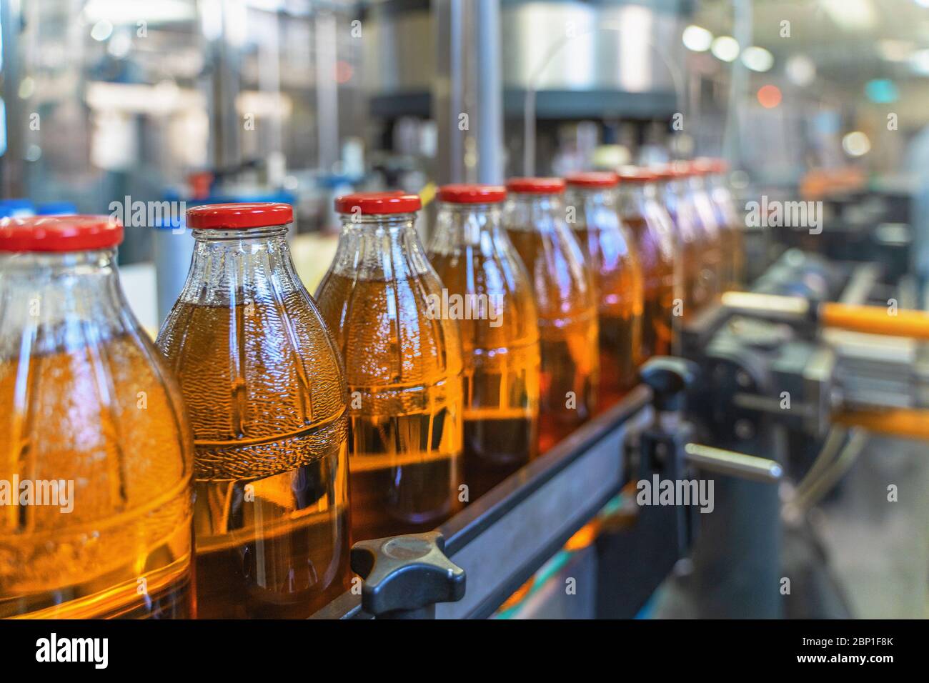 Nastro trasportatore, succo in bottiglie su impianti di produzione di bevande o interni di fabbrica, linea di produzione industriale, concentrazione selettiva. Foto Stock
