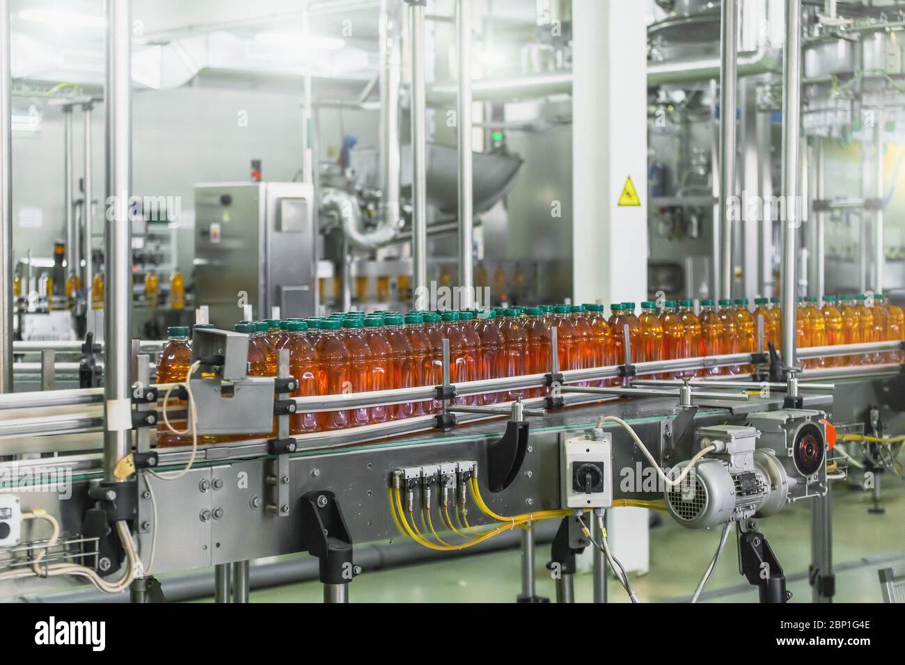 Nastro trasportatore, succo in bottiglie in impianti di produzione di bevande o interni di fabbrica, linea di produzione industriale. Foto Stock