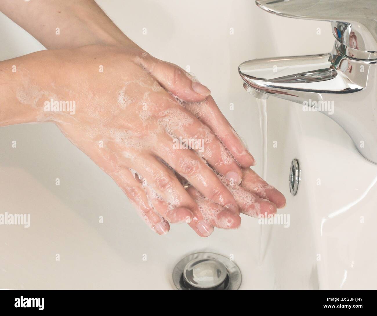 Donna lava le mani a se stessa con acqua e sapone fluenti. Protezione da infezioni Foto Stock