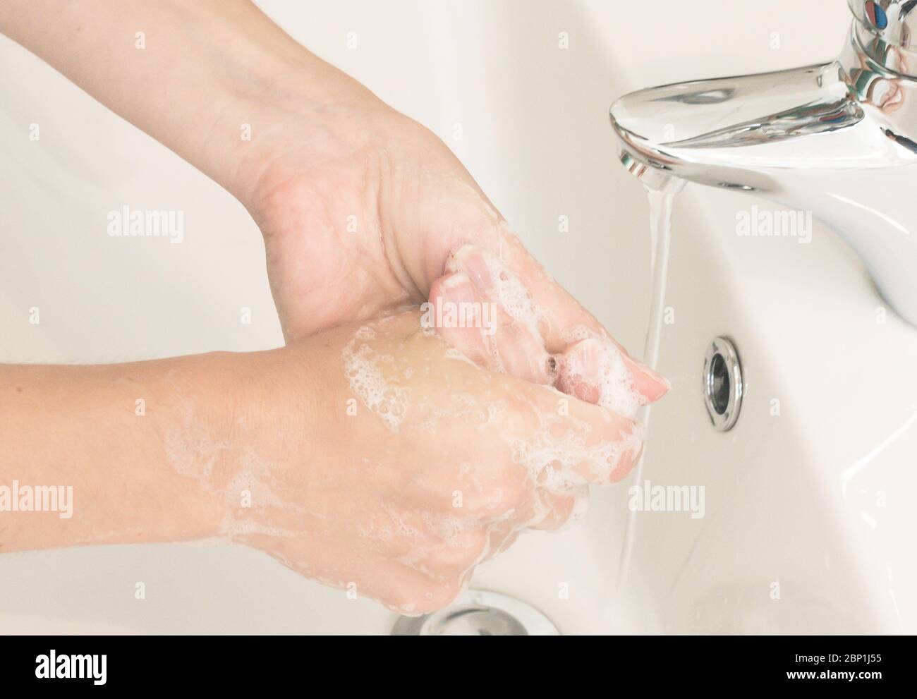 Donna lava le mani a se stessa con acqua e sapone fluenti. Protezione da infezioni Foto Stock