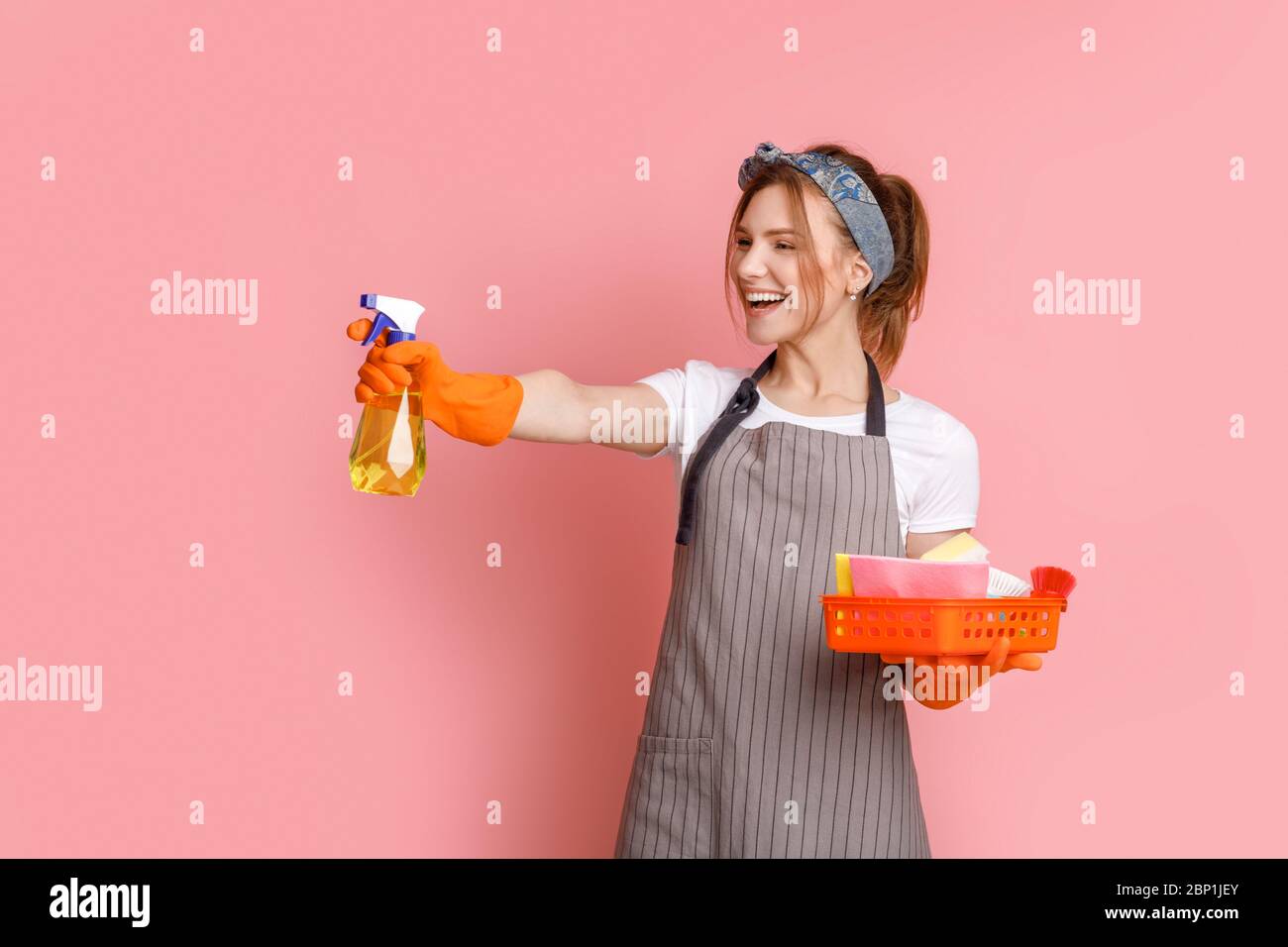Su protezione della pulizia. Cherful Housemaid con il detergente Sprayer Foto Stock