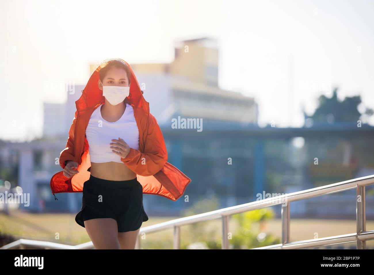Asian Young fitness sport donna in corsa e indossa una maschera per la protezione di polvere e inquinamento e la protezione del virus influenzale, influenza, coronavirus su ci Foto Stock