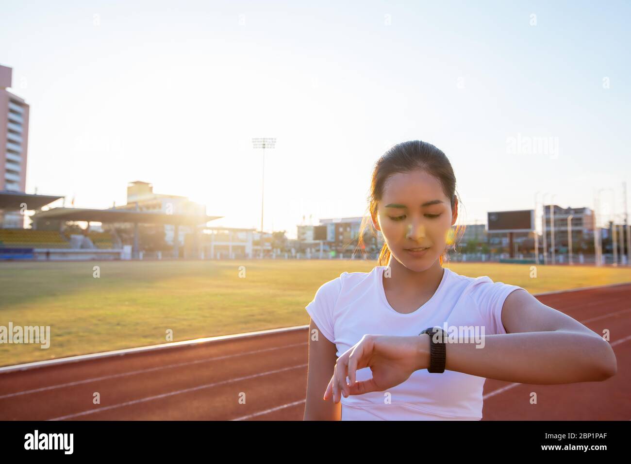 Le donne asiatiche stanno guardando l'orologio sportivo o l'orologio intelligente per fare jogging sulla pista dello stadio - stile di vita sano e concetti sportivi Foto Stock