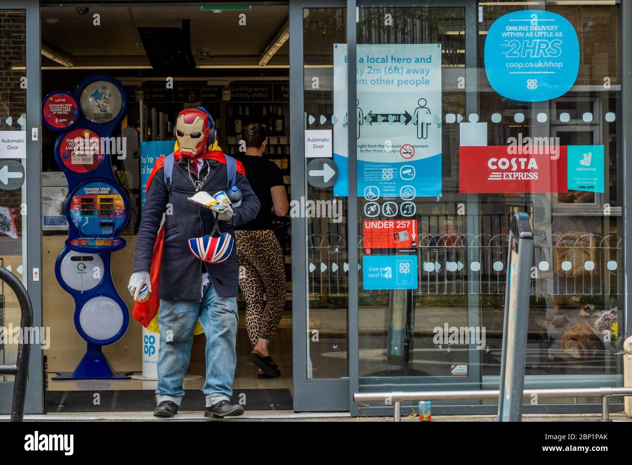 Londra, Regno Unito. 17 maggio 2020. Un uomo in una maschera Iron Man si accoda e poi si fa shopping al CO-OP in Munster Road - dove tutti sono un 'eroe locale' se rimangono 2m da altri. Il "blocco" continua per l'epidemia di Coronavirus (Covid 19) a Londra. Credit: Guy Bell/Alamy Live News Foto Stock