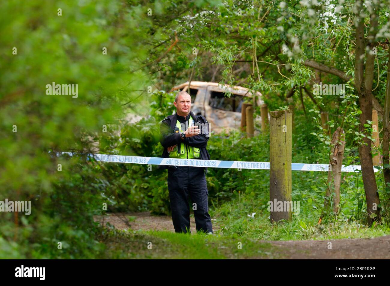 Una scena di ufficiale di crimine protegge un veicolo bruciato a Swillington, dove il conducente del veicolo schiantato fuggì dalla scena. Foto Stock