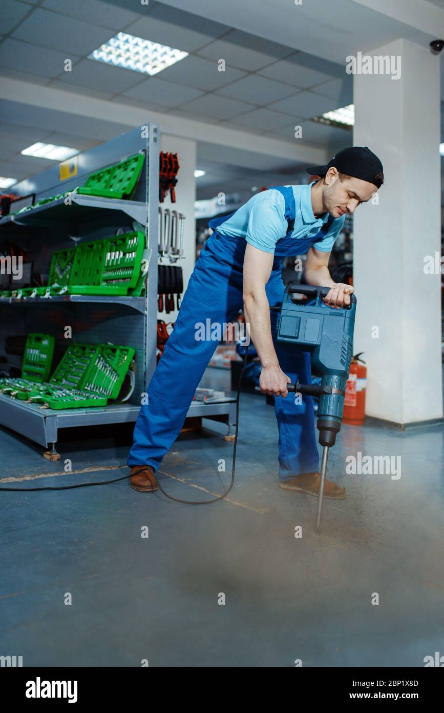 Lavoratore che esegue il test di un grande perforatore elettrico, magazzino utensili Foto Stock