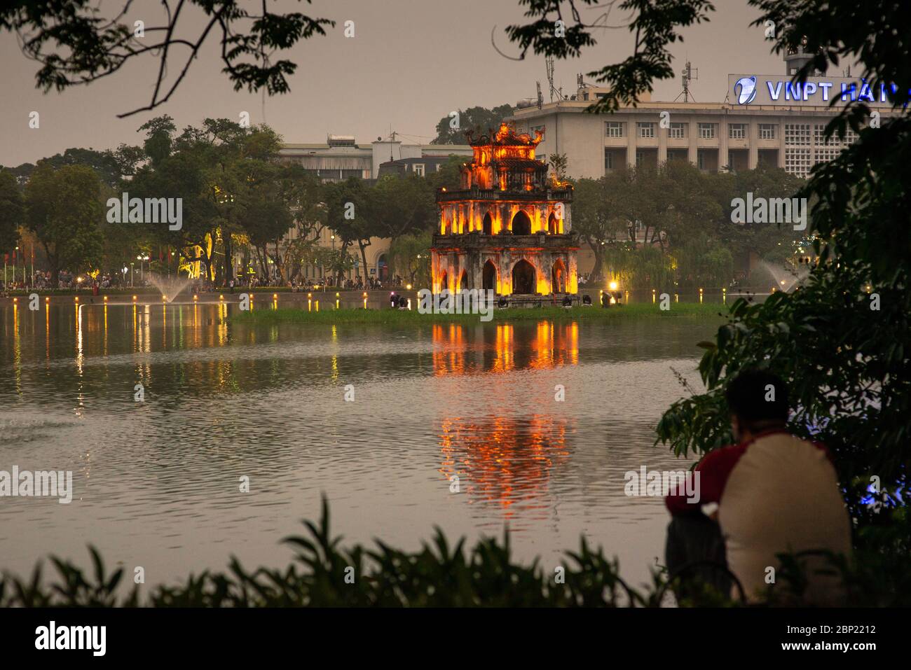 Uomo irriconoscibile, il lago Hoan Kiem e la torre delle tartarughe, preso la prima sera, Hanoi, Vietnam Foto Stock