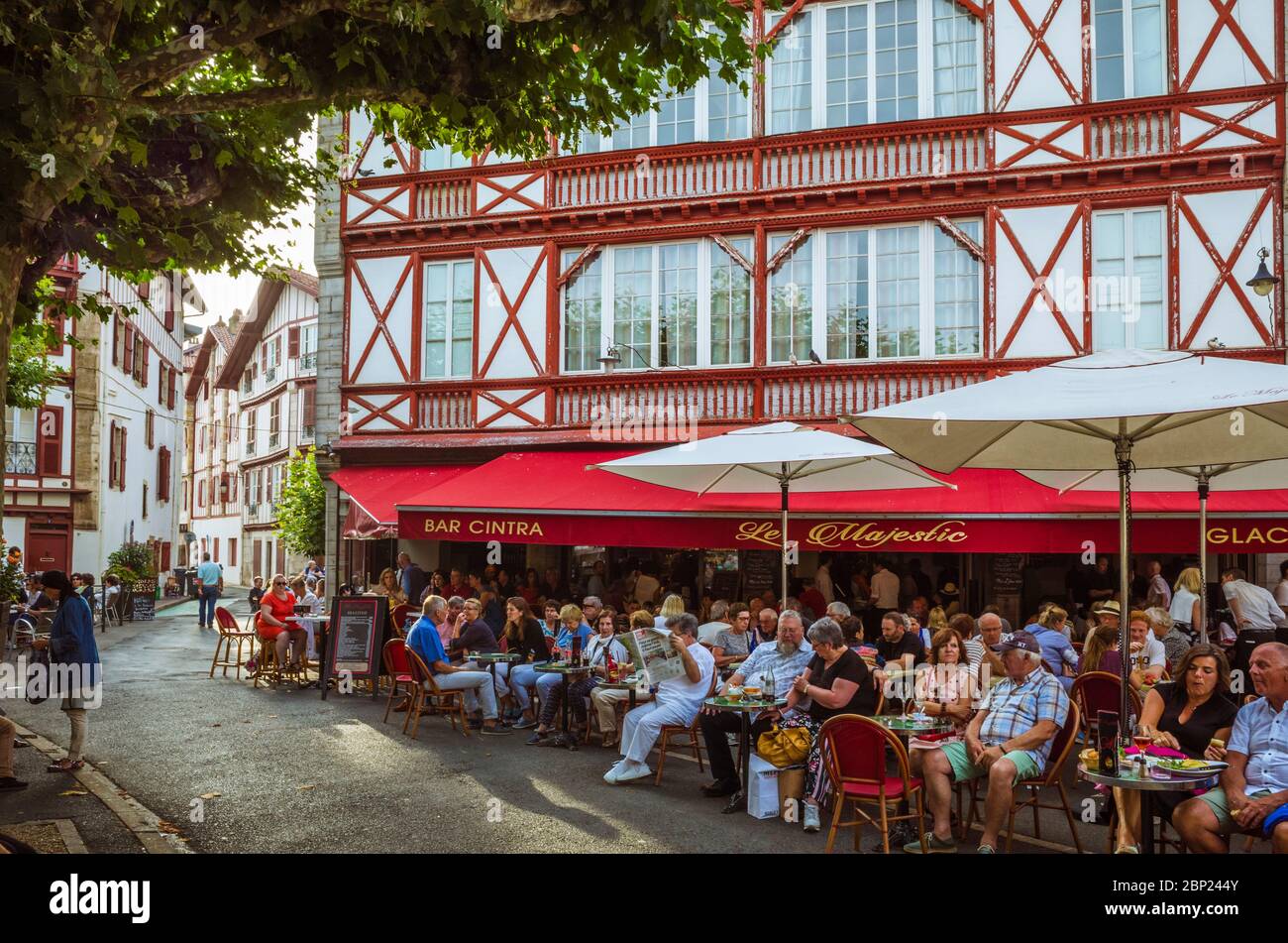 Saint Jean de Luz, Paesi Baschi francesi, Francia - Luglio 13th, 2019 : La Gente siede sulla terrazza esterna del Cafe Majestic in Place Louis XIV piazza Foto Stock