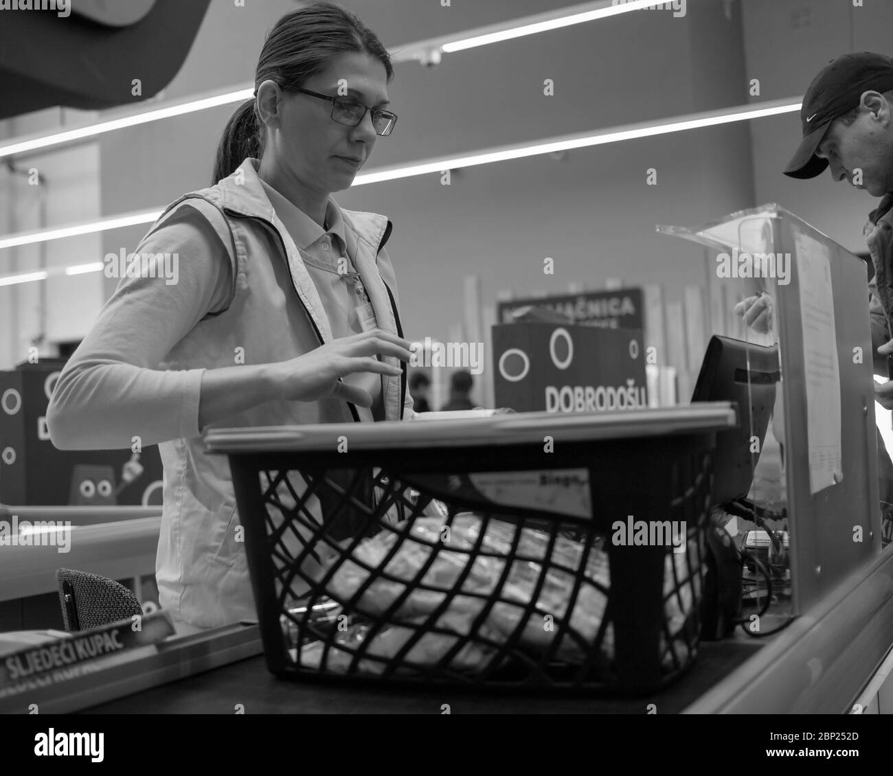 Bosanski Šamac, Bosnia-Erzegovina, 21 febbraio 2020: Donna cassiere al suo posto di lavoro in un supermercato (B/N) Foto Stock