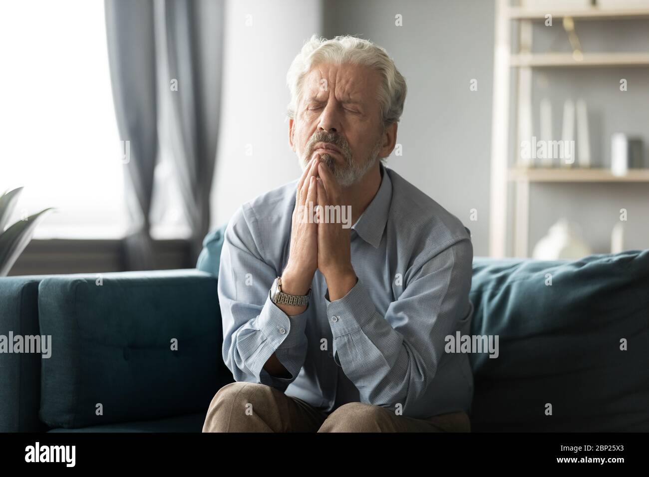 Fedele anziano di mezza età che prega Dio. Foto Stock