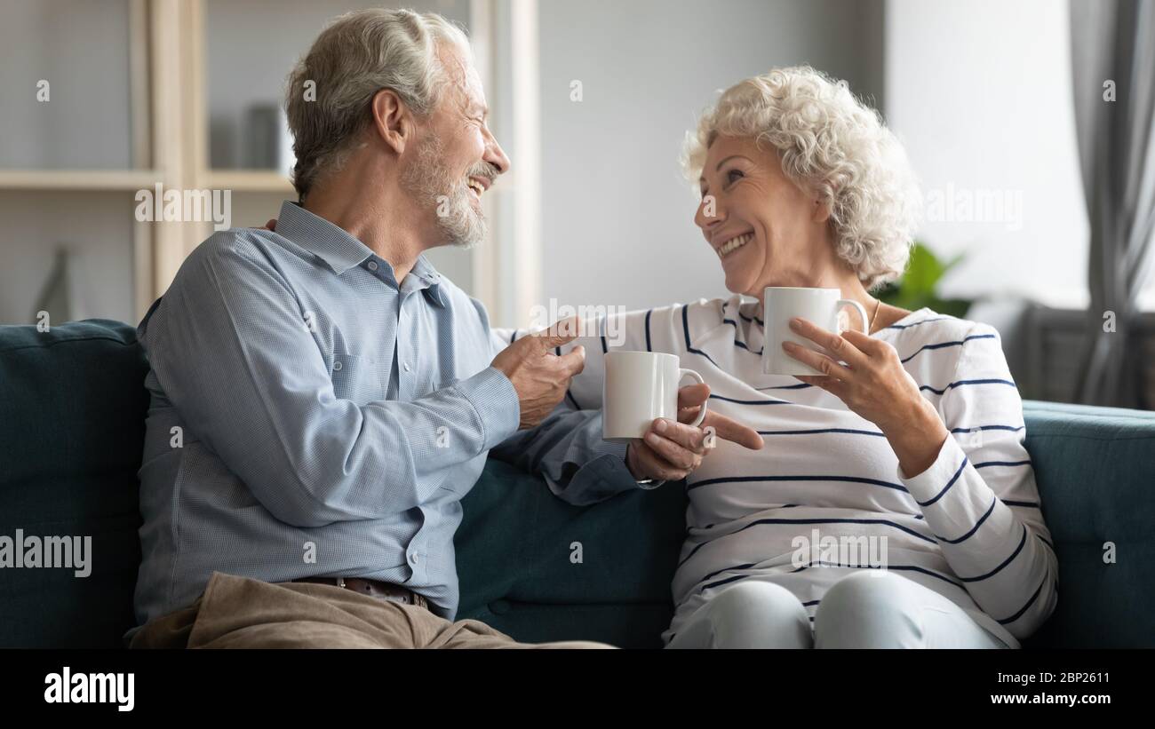 Felice coppia ritirata che tiene tazze di tè, godendo di piacevole conversazione. Foto Stock